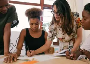 A group of colleagues lean over a table working on a document together